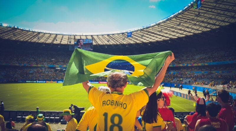Torcedor com bandeira do Brasil em estádio de futebol, referência ao clima do Brasileirão 2026